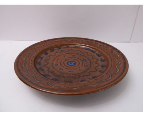 Ray Finch (Winchcombe Pottery, Gloucestershire), glaze trailed meander and dot decoration through rust slip (34cm diameter)  