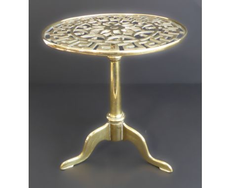 A large and heavy 19th century circular brass trivet: the top with pierced key fret border above a cast tripod base (24cm dia