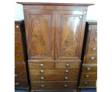 An early 19th century mahogany linen press of large proportions: the flaring cornice above two finely figured panelled doors 