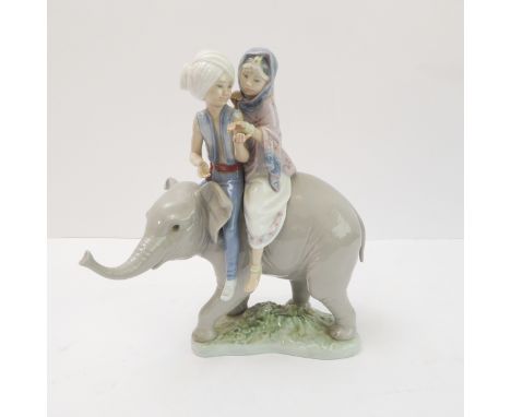 A Lladro porcelain model of two Hindu children riding upon the back of a elephant calf: impressed and printed marks to unders