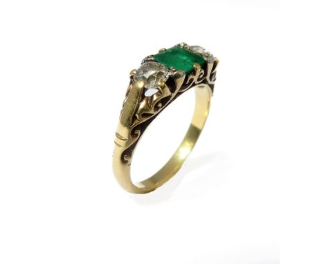 An emerald and diamond-set ring: the central rectangular step-cut emerald set to either side by an old brilliant-cut diamond 