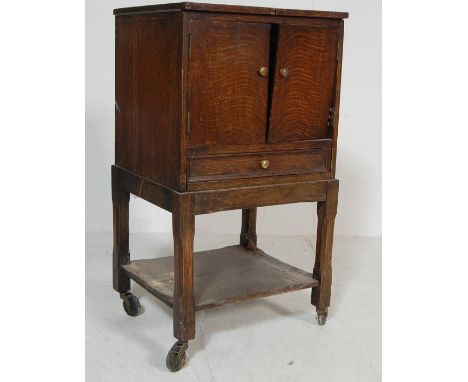 An early 20th Century Edwardian oak sewing box having tin hinged doors to the top opening to reveal a green satin lined inter