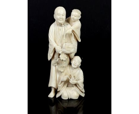 Late 19th century Japanese ivory okimono of a man carrying his son on his shoulder with another figure at his feet, signed, 1