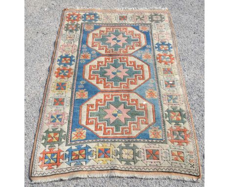 Kazak rug with three central medallions on a light blue ground with floral motifs, contained within cream ground border, 199 