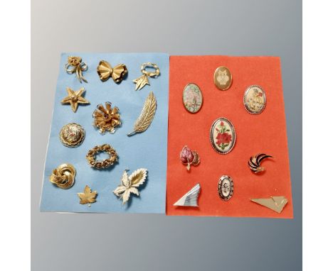 A collection of gilded metal tapestry and enamel brooches mounted on cloth 