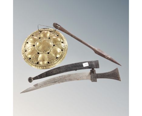 A middle-eastern short sword in leather scabbard together with a carved hardwood throwing spear and a brass plaque. 
