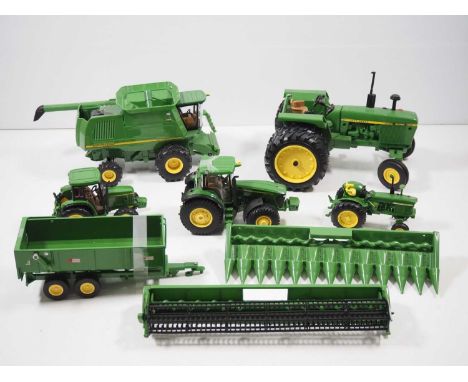 A group of larger scale diecast and plastic tractors and other farming vehicles all in John Deere livery by various manufactu