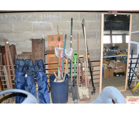 A quantity of long handled garden tools and a plastic bin of various tools, small fishing nets etc.