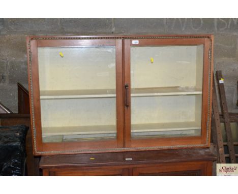 A pine two door glazed hanging shelf unit 