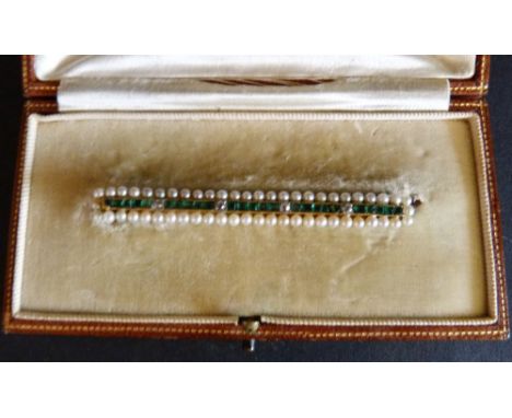 An Edwardian Yellow Gold Bar Brooch, set with four diamonds and bands of emeralds within a seed pearl surround