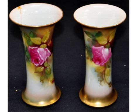 A pair of Royal Worcester hand painted and gilded vases with flared rims and decorated with roses and foliage, one signed E.S