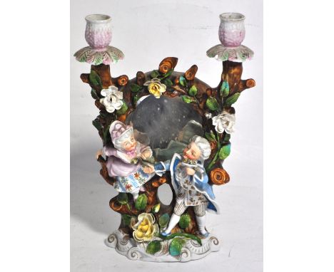 A late 19th century Continental porcelain two branch candelabrum, the twin sconces above arched back plate set with a mirror 