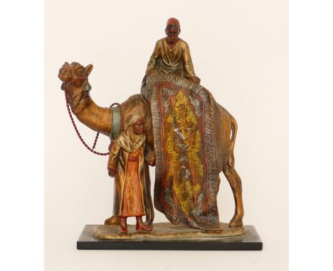 A cold painted spelter table lighter of two Arab gentlemen selling carpets on the back of a camel, in the style of Bergmann, 