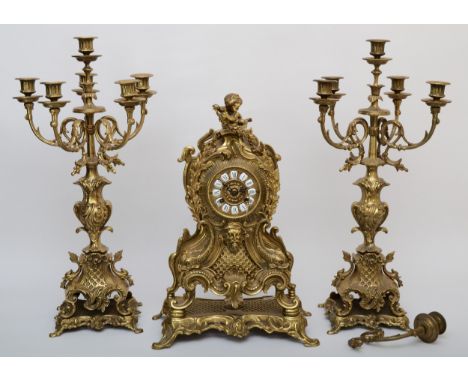 A 20th century gilt brass three piece clock garniture, the clock case cast with head of Bacchus surmounted with a cherub deco
