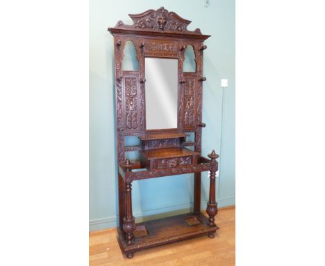 A late 19th century heavily carved oak mirror back hallstand/coat stand, the frieze carved with the head of a lion, the centr