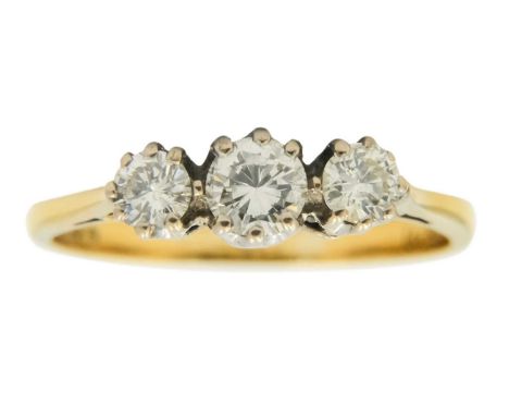 An 18ct diamond set three-stone ring. The central round brilliant cut diamond of 0.20ct approximately, flanked by two diamond
