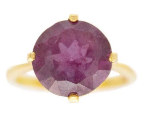 An 18ct purple corundum set ring. The round cut stone measuring 10.2 x 5.6mm, stamped 18ct, size J, 3.7g.