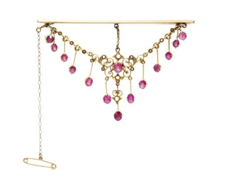 An Edwardian ruby and seed pearl set high purity gold scroll pendant, later applied to a brooch. The central open work scroll