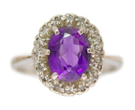 An 18ct white gold amethyst and diamond set cluster ring. The oval cut amethyst of 1.50ct estimated weight, surrounded by sma