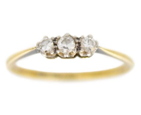 An 18ct and platinum diamond set three-stone ring. Set with three small round cut diamonds, the central stone of 0.10ct appro