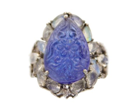 An unusual silver ring set with a carved pear-shaped Tanzanite, surrounded by moonstone. The 12ct Tanzanite foliate carved, s