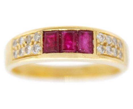 An 18ct hallmarked gold ruby and diamond set half hoop ring. Channel set with three rectangular cut rubies, flanked by 16 sma