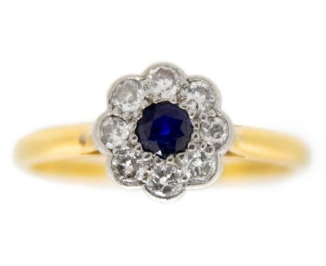 An 18ct diamond and blue sapphire set daisy cluster ring. The round cut sapphire of 0.10ct approximately, surrounded by eight