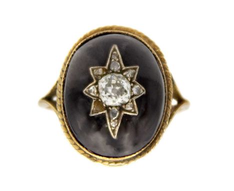 A Victorian garnet cabochon and diamond set gold ring. The oval cabochon star set with an estimated 0.30ct old mine cut diamo