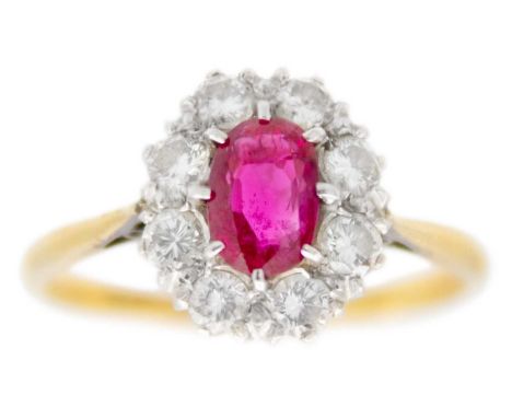 An 18ct and platinum ruby and diamond set cluster ring. The oval cut ruby of 0.58ct estimated weight, surrounded by eight rou