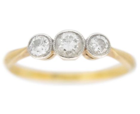 An 18ct and platinum diamond set three-stone ring. The three round cut diamonds in a millegrain setting, the principle diamon