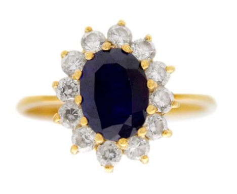 An 18ct diamond and blue sapphire set cluster ring. The oval cut sapphire measurung 8 x 6.2 x 4.3mm, surrounded by 12 small r