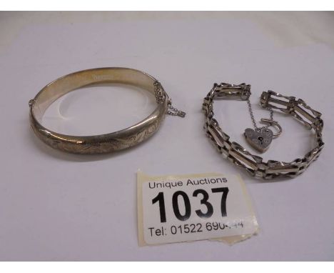 A silver gate bracelet with padlock and a silver bangle,