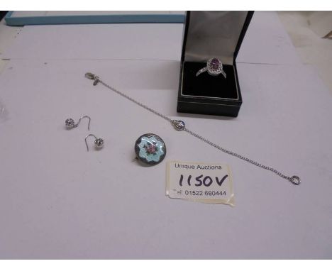 A silver bracelet, silver earrings, silver ring and an enamel brooch.