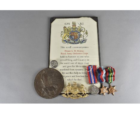 A group of three WWII medal and scroll, awarded to PTE G.W. HOLMES of the Royal Army Ordnance Corps, together with a helmet b