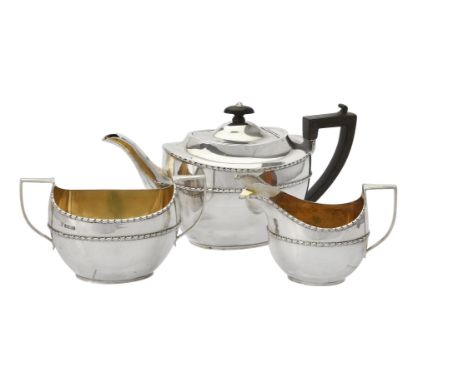 An Edwardian silver oval three piece tea set by Maxfield & Sons Ltd., Sheffield 1908, the tea pot with a composition oval fin