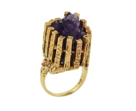 A 1970s amethyst dress ring, the amethyst crystal within an enclosed textured undulating bar setting, to polished shank, fing