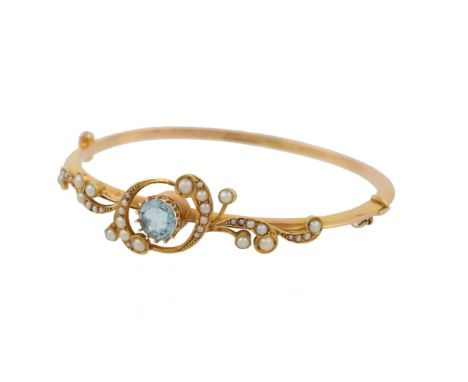 An Edwardian half pearl and aquamarine hinged bangle, circa 1910, the front with curved interlocking foliate panels set with 
