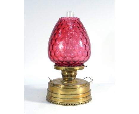 An 'Ardent Heating Lamp' with a cranberry glass shade and a brass base, h. 47 cm   CONDITION REPORT:  Chip and crack to shade