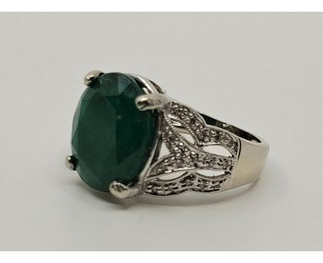 An 18ct. white gold, emerald and diamond ring, prong set mixed oval cut emerald to centre (12mm x 10mm 7mm, EEW 4.5 carats),&