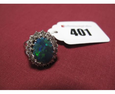 A Large Opal and Diamond Cluster Ring, the oval black opal doublet (approximately 10x14mm, damaged) claw set within single ro