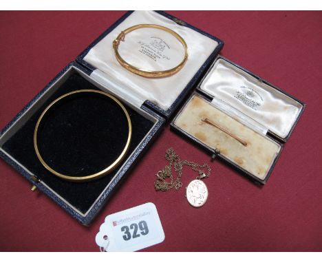 A 9ct Gold Hinged Bangle, foliate and leaf scroll engraved, hinged to snap clasp, together with a 9ct gold oval locket pendan