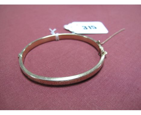 A 9ct Gold Bangle, with engraved detail, hinged to snap clasp (safety chain detached).