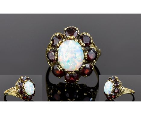 Impressive 9ct Gold Set Opal and Garnet Cluster Ring. The Oval Shaped Opal Surrounded by 8 Garnets. Marked 9ct. 6.3 grams. 