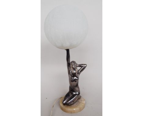 An Art Deco chrome table lamp in the form of a kneeling nude, holding aloft a glass shade, raised on a circular onyx base, 37