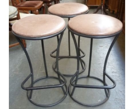 Three matching cast iron kitchen stools with light brown leatherette seats and flared tripod legs, 71cmH