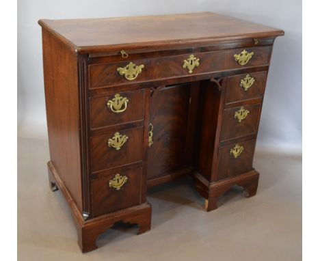 A George III Mahogany Kneehole Desk, the moulded top above a pull-out slide and a long drawer above six small drawers with ce