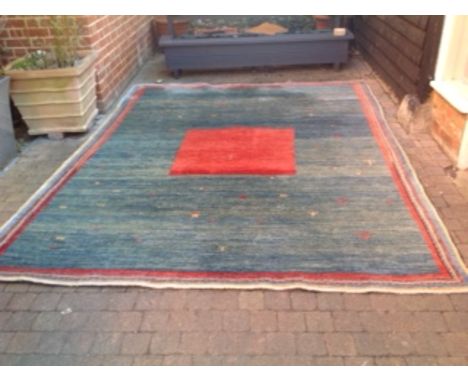 A Gabbeh Woollen Carpet with a central medallion upon a blue and red ground within multiple borders, 286 x 228 cms