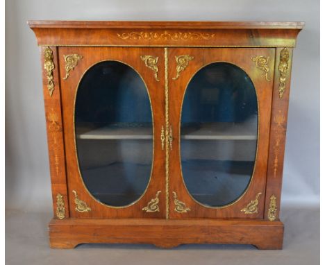 A Victorian Walnut Marquetry Inlaid and Gilt Metal Mounted Pier Cabinet, the inlaid frieze above two oval glazed doors enclos