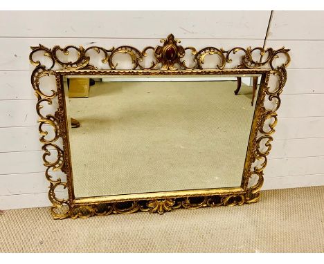 A Giltwood composition mirror with rectangular plate and scrolling border. (104 cm x 90 cm)