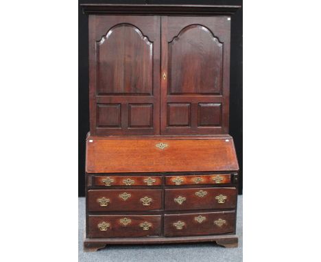 An unusual and substantial mid-18th century oak bureau bookcase/cabinet, outswept cornice above a pair of raised and fielded 